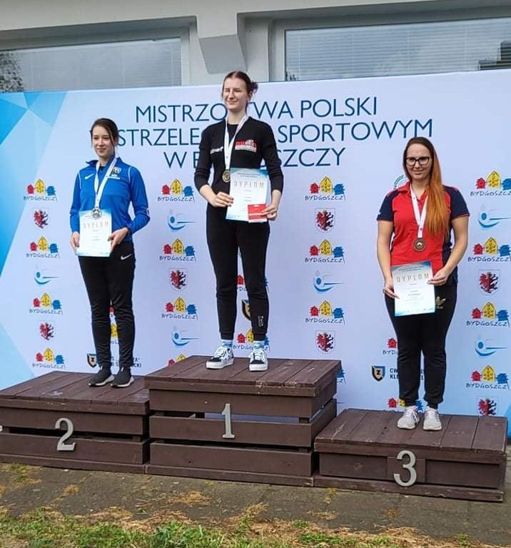 zdjęcie przedstawia absolwentkę UPH Kingę Kowalik brązową medalistkę Mistrzostw Polski w strzelectwie sportowym oraz dwie inne zwyciężczynie